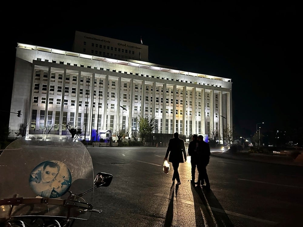 Syrian citizens walk in front the building of the Syrian Central Bank in Damascus, Syria, Saturday, December 7, 2024 (AP)