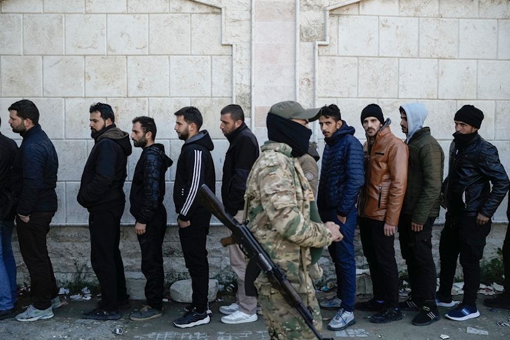 Members from the Syrian Arab Army line up to register with Syrian rebels as part of an 