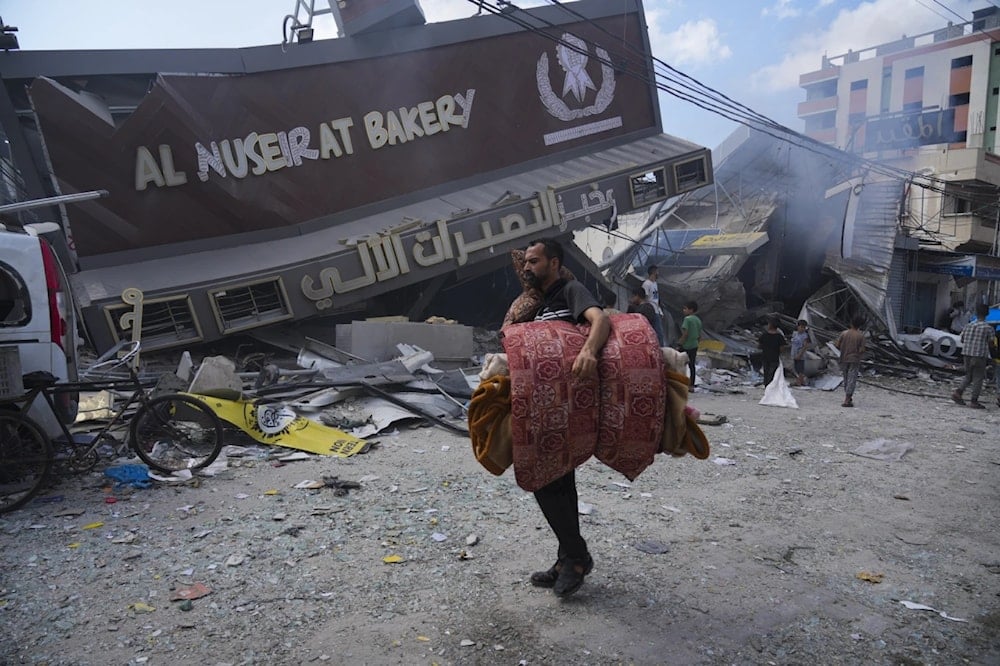 Palestinians walk past the Al Nuseirat Bakery, destroyed in an Israeli airstrike, in Nusseirat refugee camp Gaza Strip, Wednesday, Oct. 18, 2023. (AP)