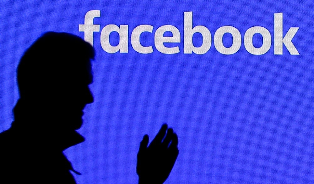 A man passes a facebook screen at the Gamescom in Cologne, Germany, Tuesday, Aug. 20, 2019. (AP)