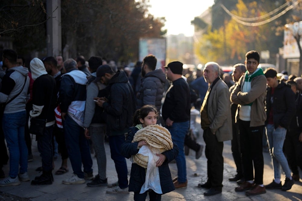 Residents stand in queue as they wait to buy bread from a bakery in the city of Aleppo, Syria, Saturday, Dec. 14, 2024. (AP Photo/Khalil Hamra)