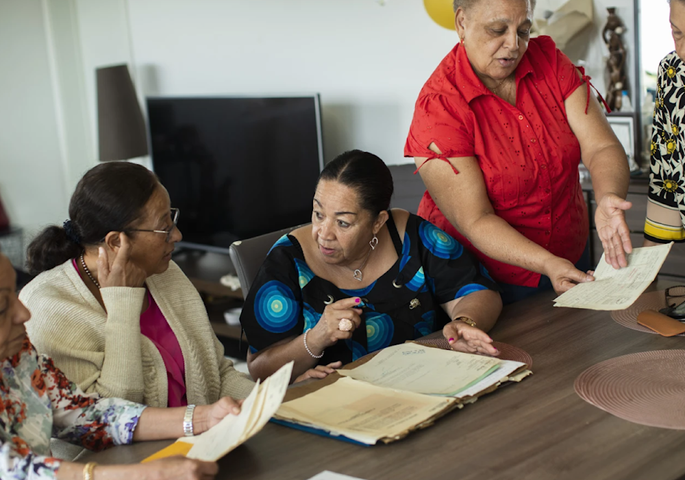 Marie-Jose Loshi, Monique Bitu Bingi, Lea Tavares Mujinga, Simone Ngalula, and Noelle Verbeeken speak with each other as they look over papers in Brussels, Belgium on June 29, 202. (AP)