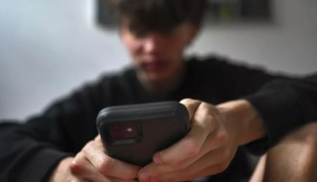 A teenager uses his mobile phone to access social media in Sydney, Australia, on November 13, 2024. (AP