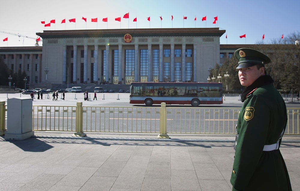 A paramilitary police officer stands guard in Tiananmen Square with the Great Hall of the People in the background in Beijing, Tuesday, March 1, 2011. 