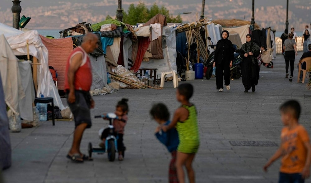 People walk past tents set up as temporary shelters by displaced families fleeing the Israeli airstrikes in the south and Dahiyeh, on Beirut's corniche, Lebanon, Monday, Oct. 14, 2024. (AP)