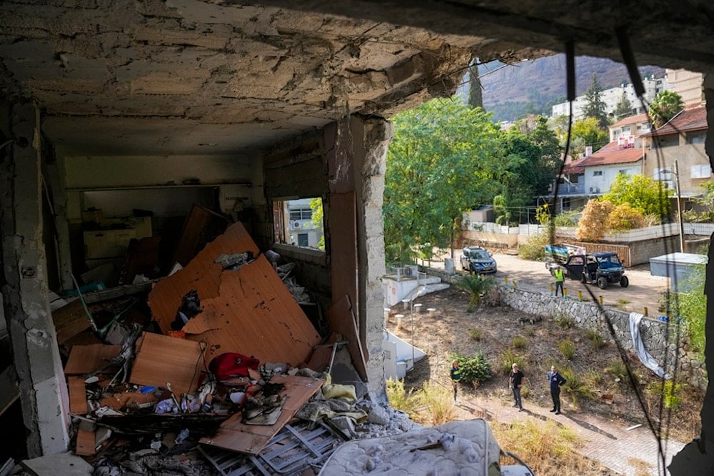 Israeli occupation settlers stand next to the site where a rocket fired from Lebanon hit a residential building in Kiryat Shmona, in northern occupied Palestine, Nov. 20, 2024. (AP)