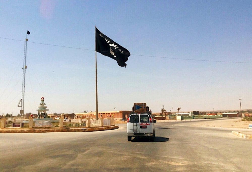 This Tuesday, July 22, 2014 photo shows a motorist passing by a flag of the Islamic State group in central Rawah, 175 miles (281 kilometers) northwest of Baghdad, Iraq. (AP)