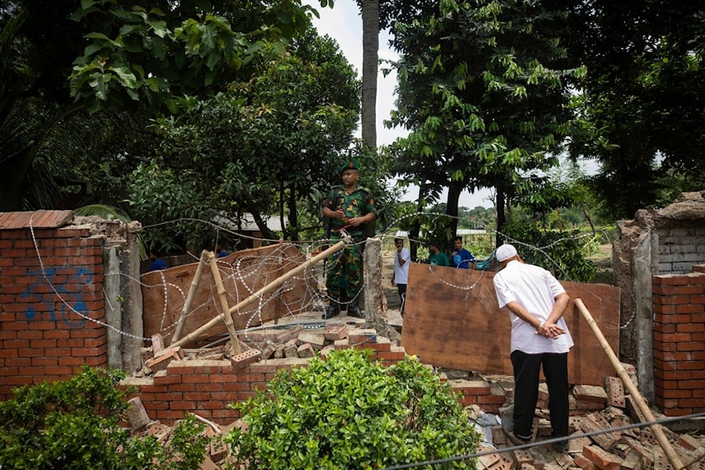 A man peeks inside the boundary wall of the vandalised house of Sheikh Hasina, who resigned as Prime Minister on Monday, in Dhaka, Bangladesh, Tuesday, Aug. 6, 2024. (AP)