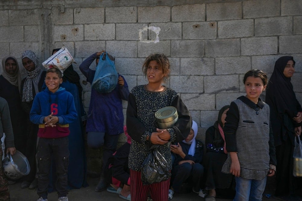 Palestinian children wait for food at a distribution center in Deir al-Balah, Gaza Strip, Tuesday, Dec. 17, 2024. (AP Photo/Abdel Kareem Hana)