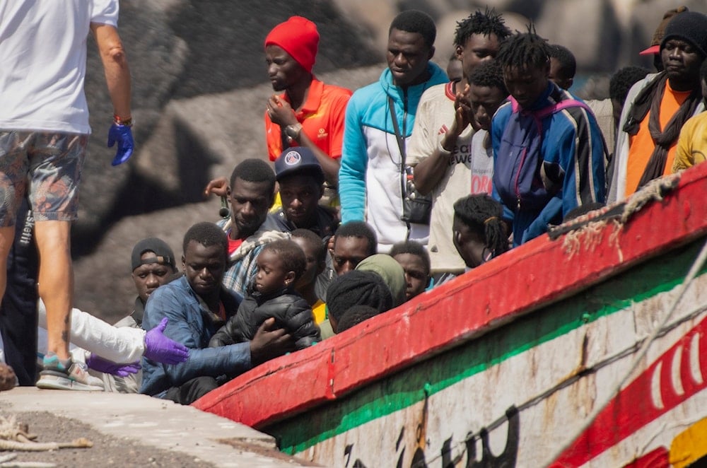 A child is carried ashore from a crowded wooden boat as they arrive at the port in La Restinga on the Canary island of El Hierro, Spain, on August 18, 2024. (AP)