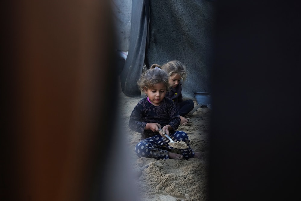 Grandchildren of Reda Abu Zarada, displaced from Jabaliya in northern Gaza, play with sand next to their tent at a camp in Khan Younis, Gaza Strip, on December 19, 2024. (AP)