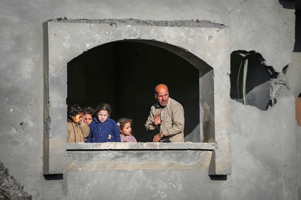 Neighbours watch the funeral procession of the victims of an Israeli occupation strike on a home in Deir al-Balah, central Gaza Strip, Palestine, amid ongoing genocide, on Dec. 22, 2024. (AP)