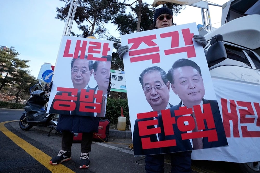 Protesters hold banners showing images of impeached President Yoon Suk Yeol, right, and acting President Han Duck-soo during a rally demanding Han's impeachment outside of the National Assembly in Seoul, South Korea, Dec. 27, 2024 (AP)