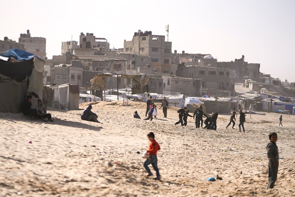 Children play on the sand in a camp for internally displaced Palestinians at the beachfront in Deir al-Balah, central Gaza Strip, Friday, Dec. 27, 2024 (AP)