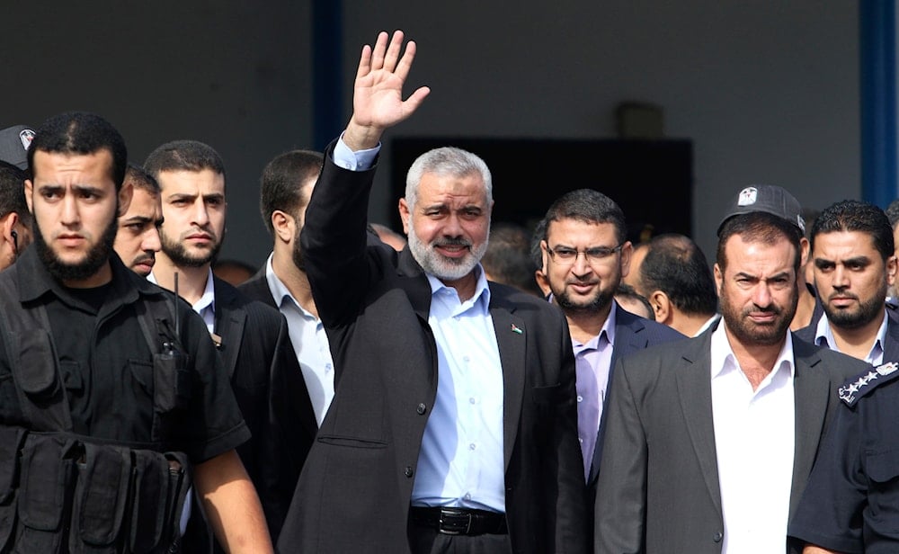 Gaza's Hamas Prime Minister Ismail Haniyeh, center, gestures at the Rafah border crossing between Egypt and Gaza, Tuesday, Oct. 18, 2011