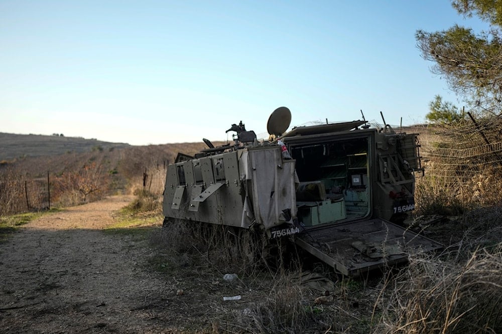 A damaged Israeli occupation forces vehicle lies in a field in northern occupied Palestine near the Lebanon border, Friday, December 6, 2024 (AP)