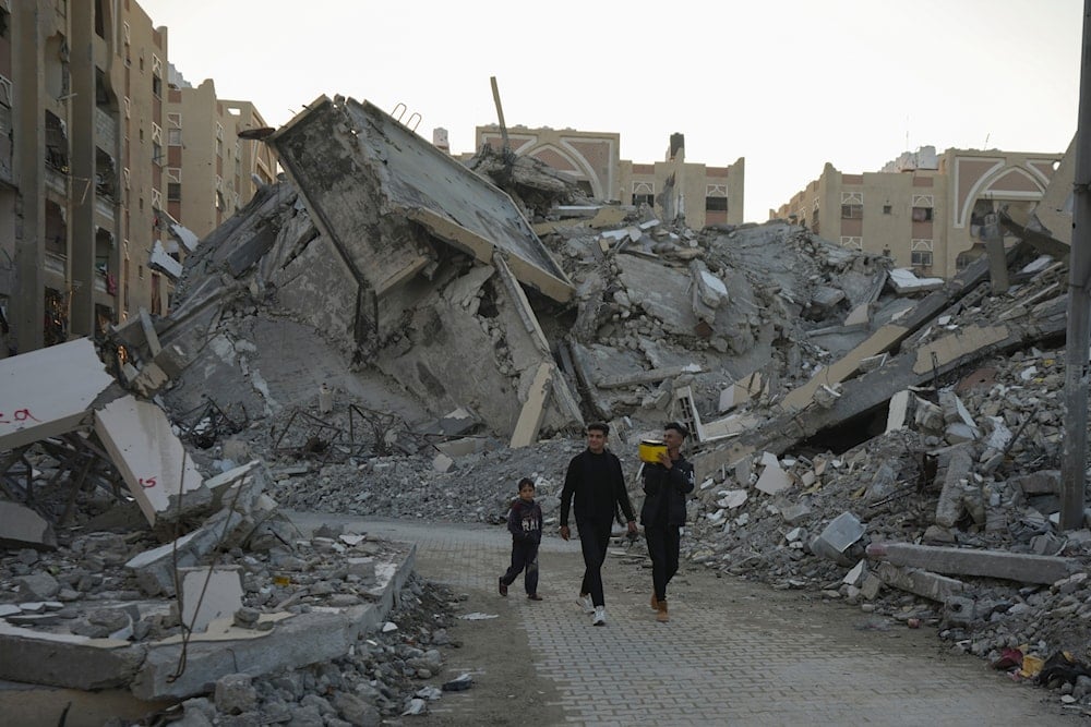 Young Palestinians walk amongst rubble of destroyed buildings at a neighbourhood in Khan Younis, Gaza Strip, on December 1, 2024. (AP)