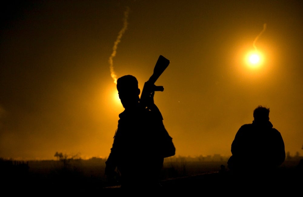 A U.S.-backed Syrian Democratic Forces (SDF) fighter watches illumination rounds light up Baghouz, Syria on March 12, 2019. (AP)