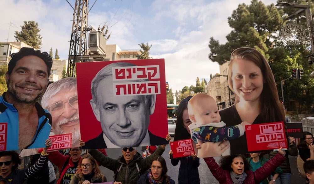 Protest for Israeli settlers urging a prisoner exchange deal in al-Quds, occupied Palestine, on Nov. 18, 2024, holding photos of their loved ones. One placard reads, 'Cabinet of death.' (AP)