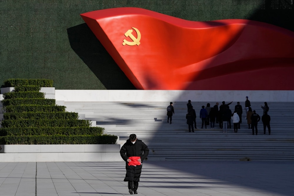 FILE - A worker folds a flag near a giant sculpture of the Chinese Communist Party flag outside the Museum of the Communist Party of China, in Beijing, Nov. 12, 2021. (AP)