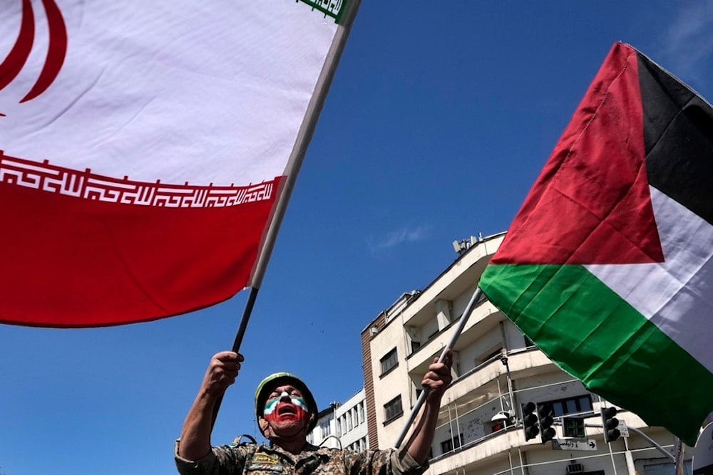 Man waves Iranian and Palestinian flags in the annual rally to mark Quds Day, in support of Palestinians, in Tehran, Iran, Friday, April 5, 2024 (AP)