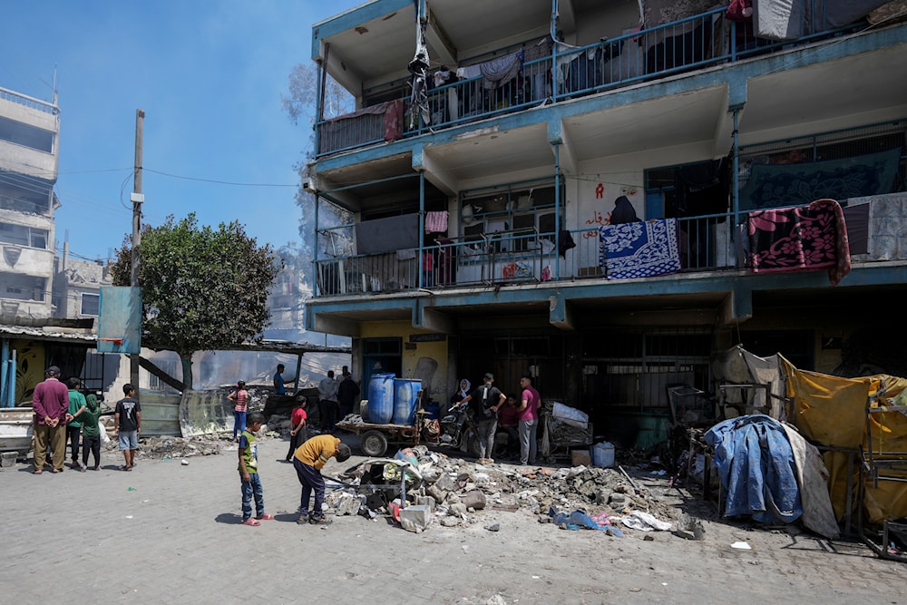 Palestinians stand next to the site hit by an Israeli strike on a school run by UNRWA, the UN agency helping Palestinian refugees, in Nuseirat, Gaza Strip, May 14, 2024 (AP)