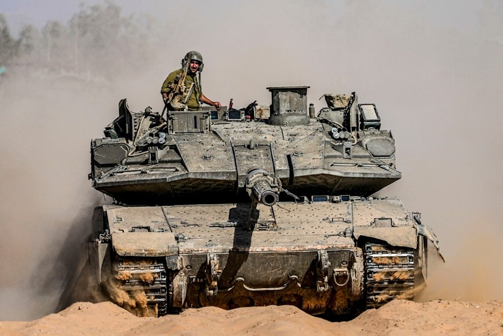 Israeli soldiers drive a tank at a staging ground near the separation line with the Gaza Strip, in southern occupied Palestine, Sunday, May 5, 2024. (AP Photo/Tsafrir Abayov)