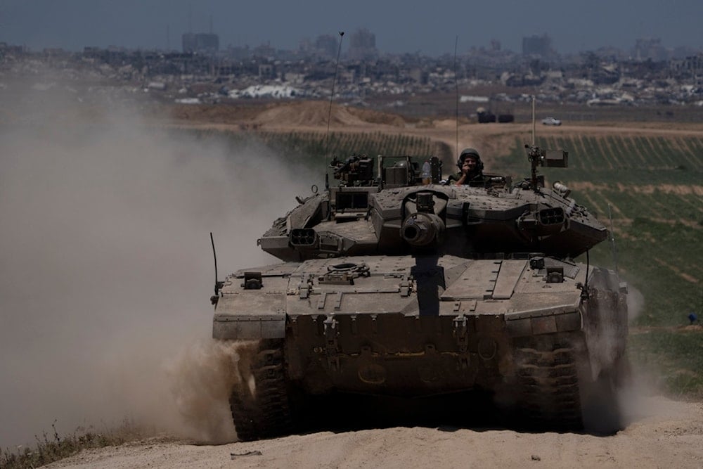 Israeli occupation soldiers move on the top of a tank near the Gaza border, as seen from southern occupied Palestine, Thursday, May 16, 2024. (AP)