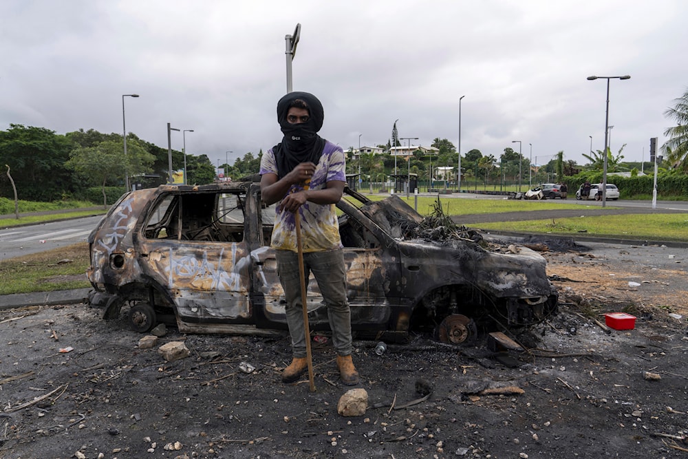 A man stands in front a burnt car after unrest in Noumea, New Caledonia, Wednesday May 15, 2024. (AP)