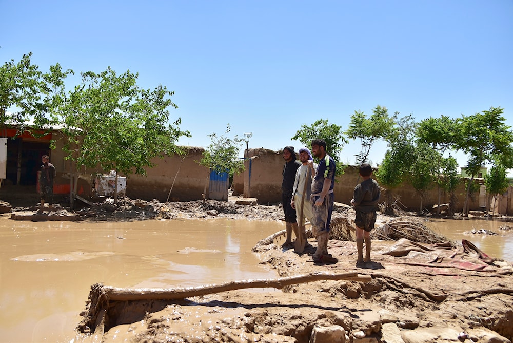 People stand near damaged homes after heavy flooding in Baghlan province, in northern Afghanistan, Sunday, May 12, 2024. (AP)