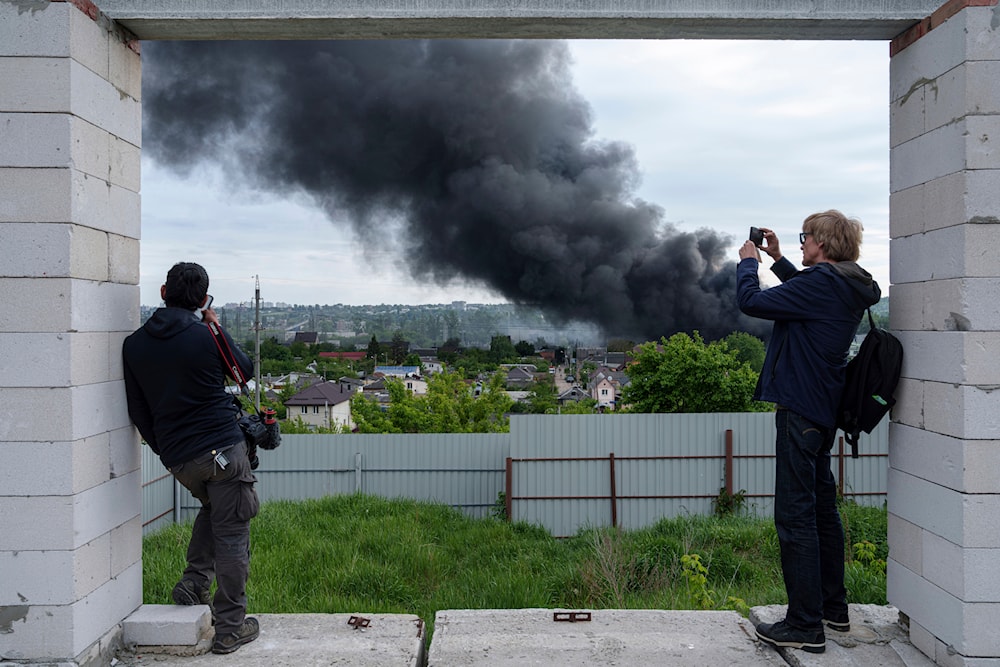 Foreign journalists report from an observation point while smoke rises after a Russian strike in Kharkiv on May 17, 2024. (AP)