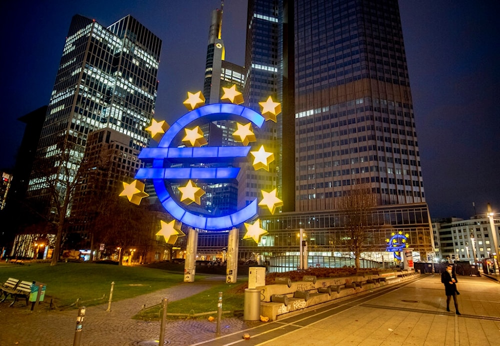 A man walks in front of the Euro sculpture in Frankfurt, Germany, March 11, 2021 (Associated Press)