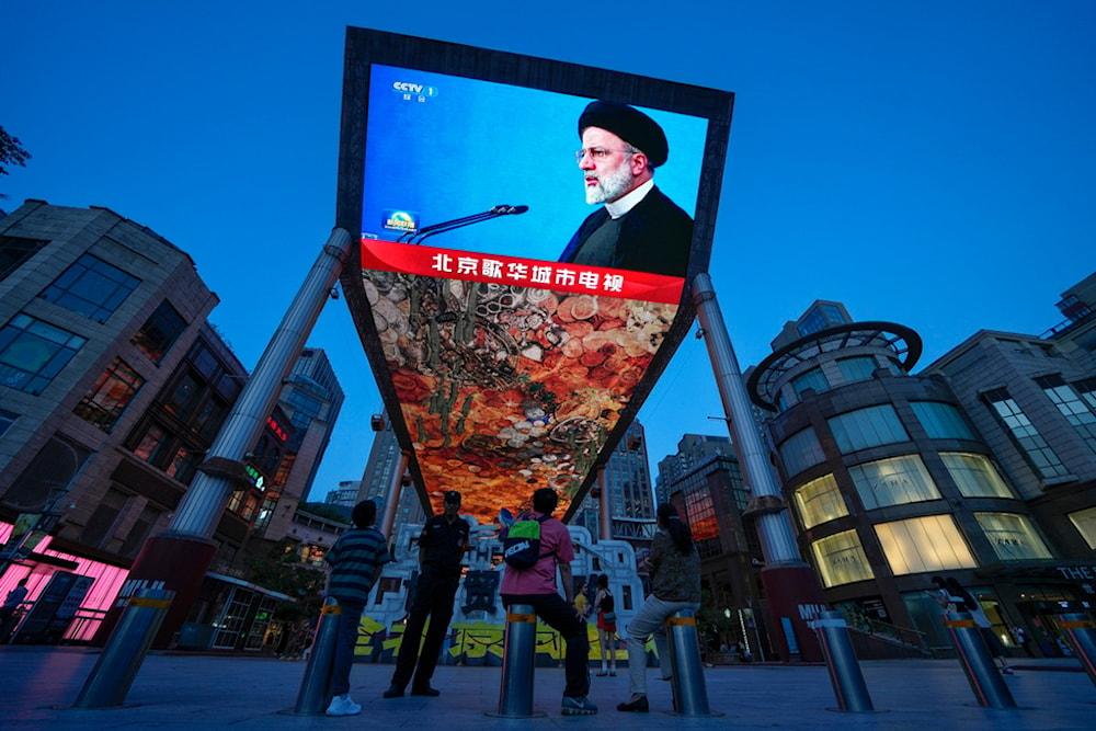 Residents watch a large screen showing a footage of Iranian President Ebrahim Raisi, during the evening news broadcast on his death, at an outdoor shopping mall in Beijing, Monday, May 20, 2024. (AP)