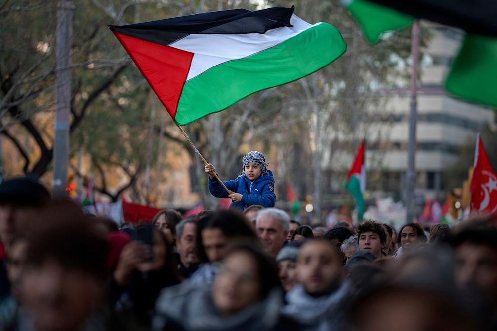 A boy waves a Palestinian flag as demonstrators march during a protest in support of Palestinians and calling for an immediate ceasefire in Gaza, in Barcelona, Spain, on Jan. 20, 2024.(AP)