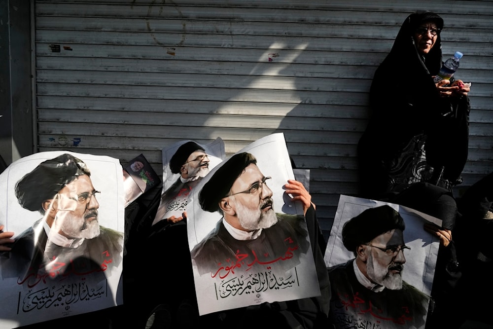 Mourners hold posters of the late Iranian President Ebrahim Raisi during a funeral ceremony for him and his companions, in Tehran, Iran, Wednesday, May 22, 2024 (AP)