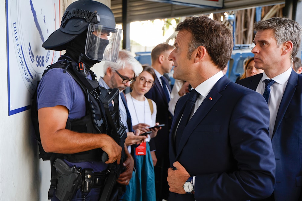 French President Emmanuel Macron talks to a policeman upon his arrival at the central police station in Noumea, New Caledonia, Thursday, May 23, 2024.(AP)