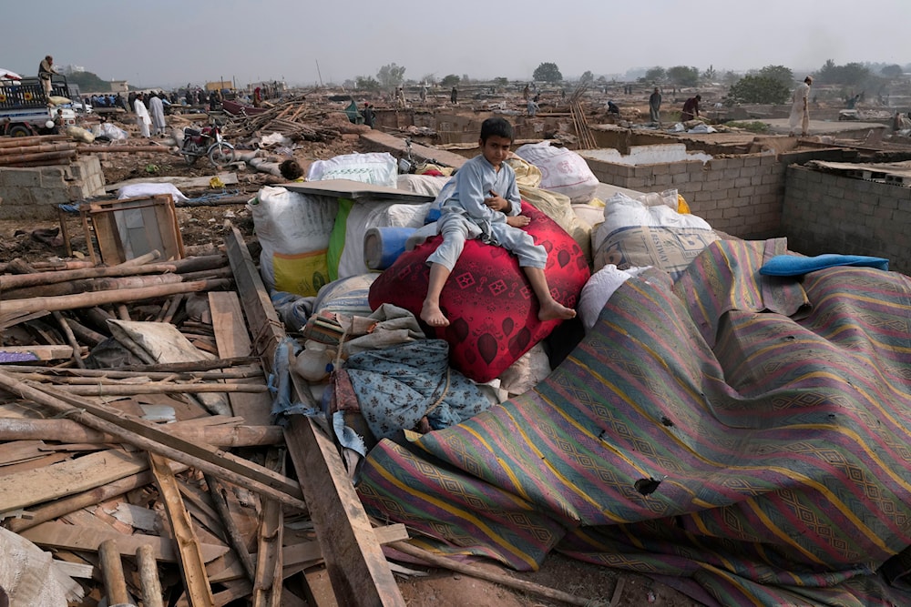 An Afghan boy sits over his family's belongings retrieved from their damaged mud homes demolished by authorities on the outskirts of Islamabad, Pakistan, Wednesday, Nov. 1, 2023. (AP)