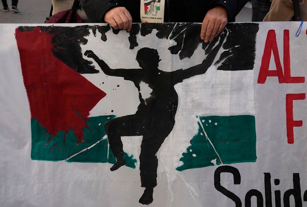 A protester takes part in a demonstration march carrying a banner showing the Palestinian flag, in support of Palestinians in Madrid, Spain, Saturday, Dec. 2, 2023. (AP)