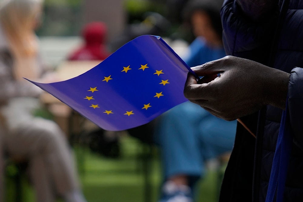 A man holds a European Union flag as he walks outside the European Commission building during Europe Day celebrations in Brussels on Saturday, May 4, 2024. (AP)