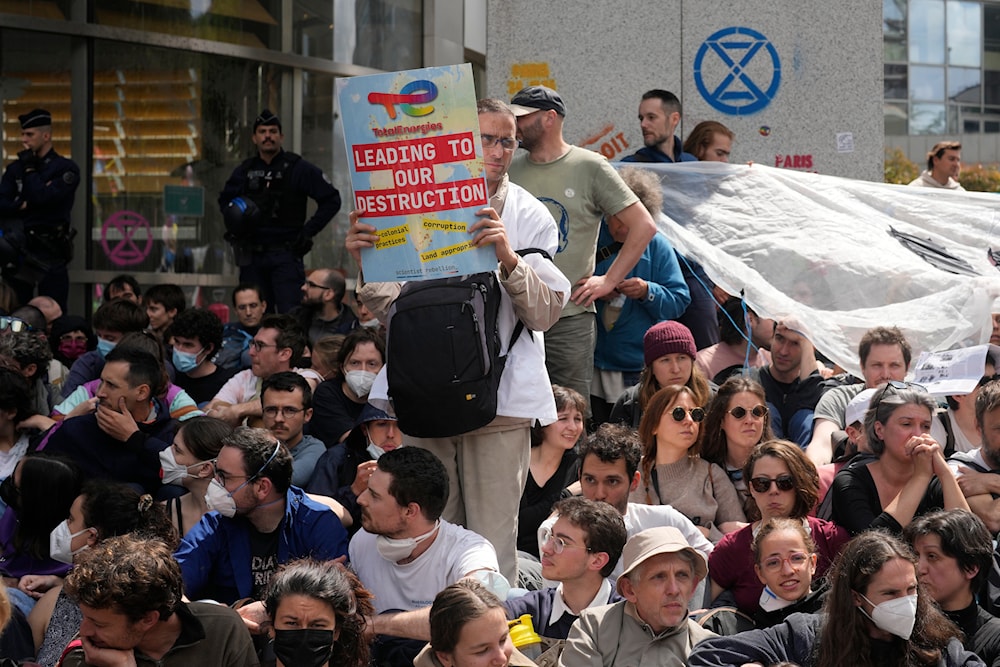 Climate activists gather outside the French asset manager Amundi headquarters to denounce the group's holding in oil major TotalEnergies, Friday, May 24, 2024 in Paris. (AP)