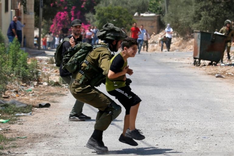 Israeli occupation forces detain a Palestinian child in the Palestinian village of Kfar Qaddum in the occupied West Bank on August 23, 2019. (AFP)