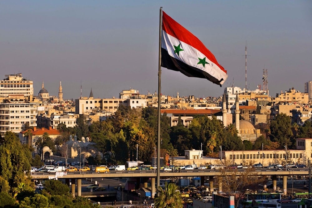 A Syrian national flag waves as vehicles move slowly on a bridge during rush hour, in Damascus, Syria, on Feb. 28, 2016. (AP)