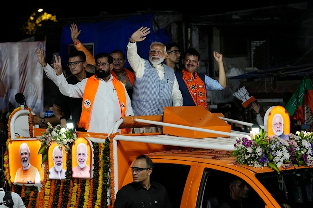 Indian Prime Minister Narendra Modi, center, waves to his supporters from a vehicle during a road show, in Mumbai, India, Wednesday, May 15, 2024. (AP Photo/Rajanish Kakade)