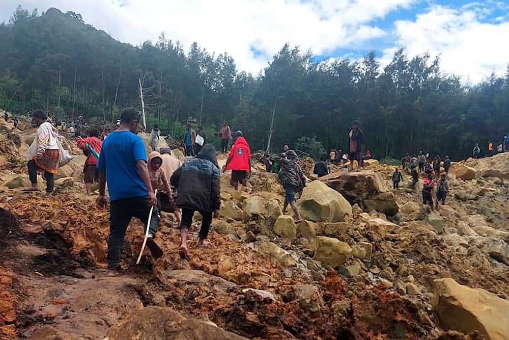 In this photo provided by the International Organization for Migration, people cross over the landslide area to get to the other side in Yambali village, Papua New Guinea, Friday, May 24, 2024. (AP)