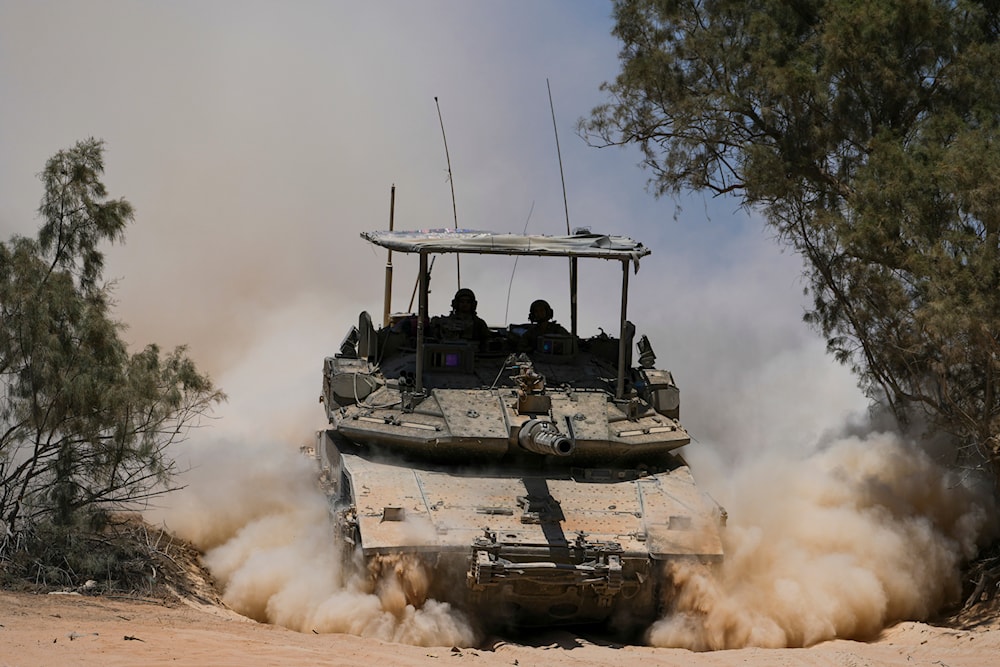 Israeli occupation forces soldiers drive a tank in the Gaza envelope, in southern occupied Palestine, May 29, 2024 (AP)