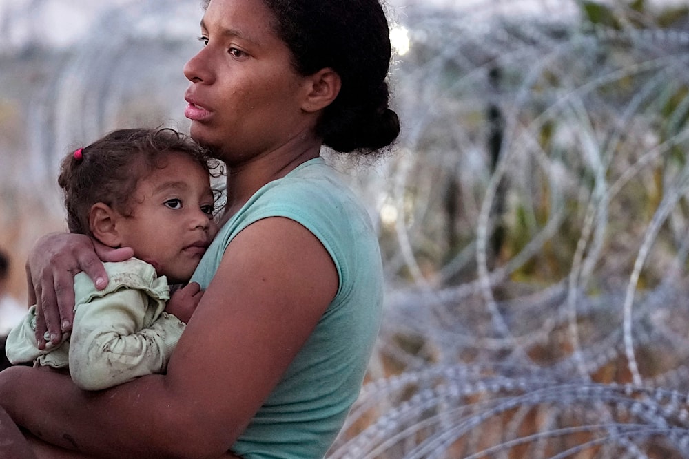 A woman carries her child after she crossed the Rio Grande and entered the US from Mexico to be processed by U.S. Customs and Border Protection, Saturday, Sept. 23, 2023, in Eagle Pass, Texas. (AP)