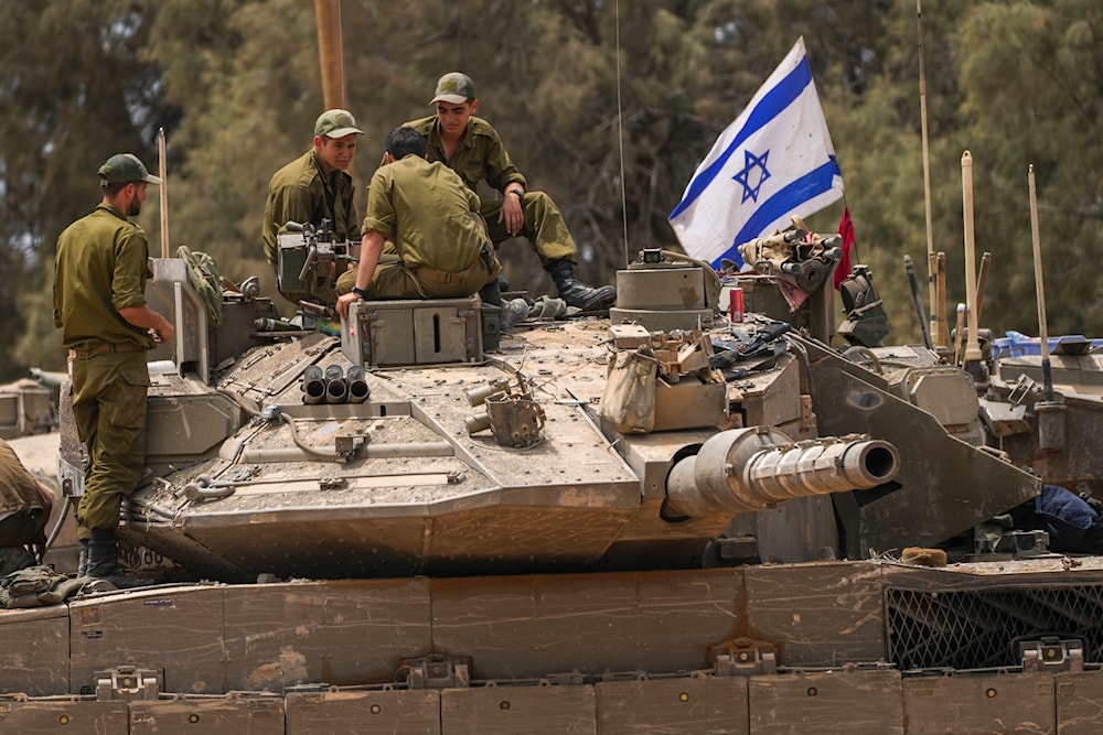 Israeli soldiers work on a tank near the Gaza border, in southern occupied Palestine on May 29, 2024. (AP)