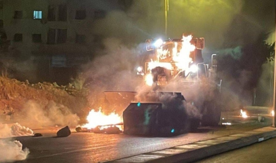 An Israeli bulldozer burns after being targeted by Resistance fighters with an explosive device in Balata refugee camp, West Bank