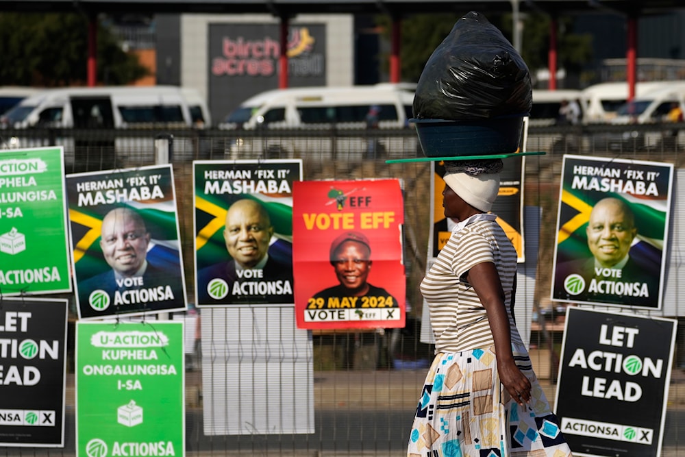 A woman walks past election posters in Tembisa, east of Johannesburg, South Africa, Tuesday, May 28, 2024, ahead of the elections on Wednesday May 29. (AP)