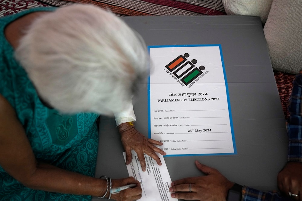 An elderly woman signs a paper after casting her vote at home, in New Delhi, India, on May 17, 2024. (AP)